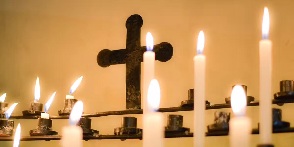 candles burning in front of a cross in a parish