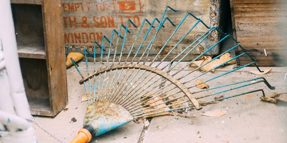 a rake and leafs laying on the ground next to wood boxes