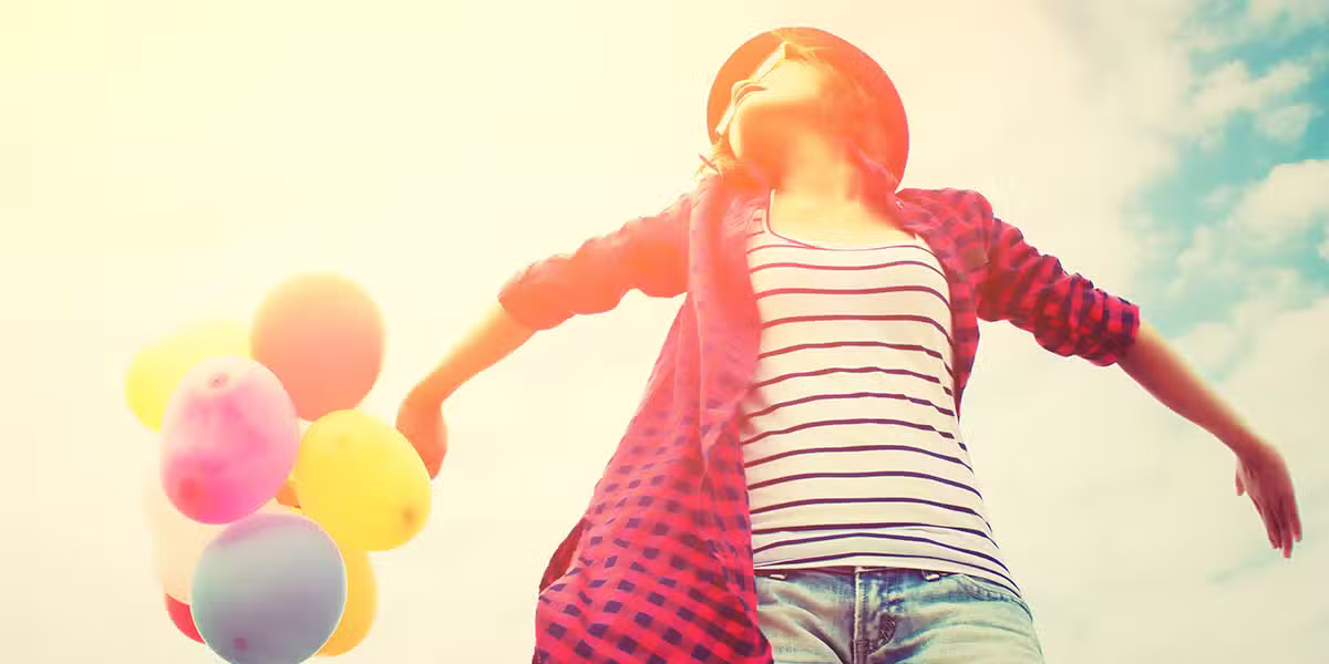 choose joy; joyful woman wearing pink and holding colorful balloons