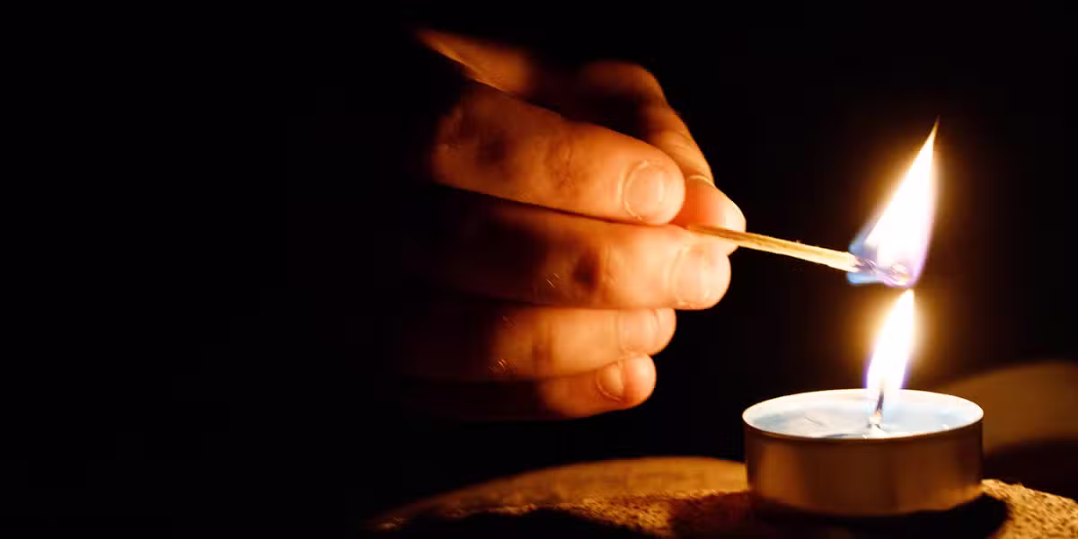 christmas eve: a holy pause; a hand lighting a candle with a match