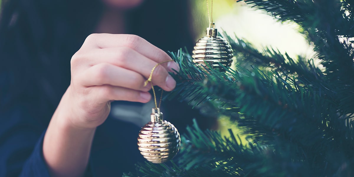 the beauty of the incarnation; hand putting an ornament on the christmas tree