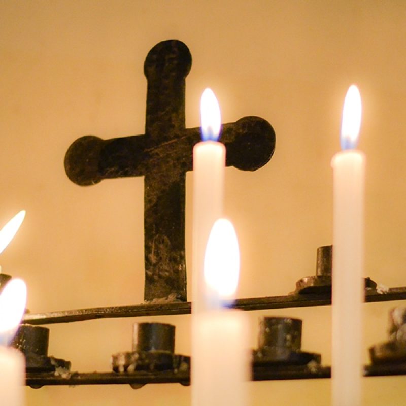 candles burning in front of a cross in a parish