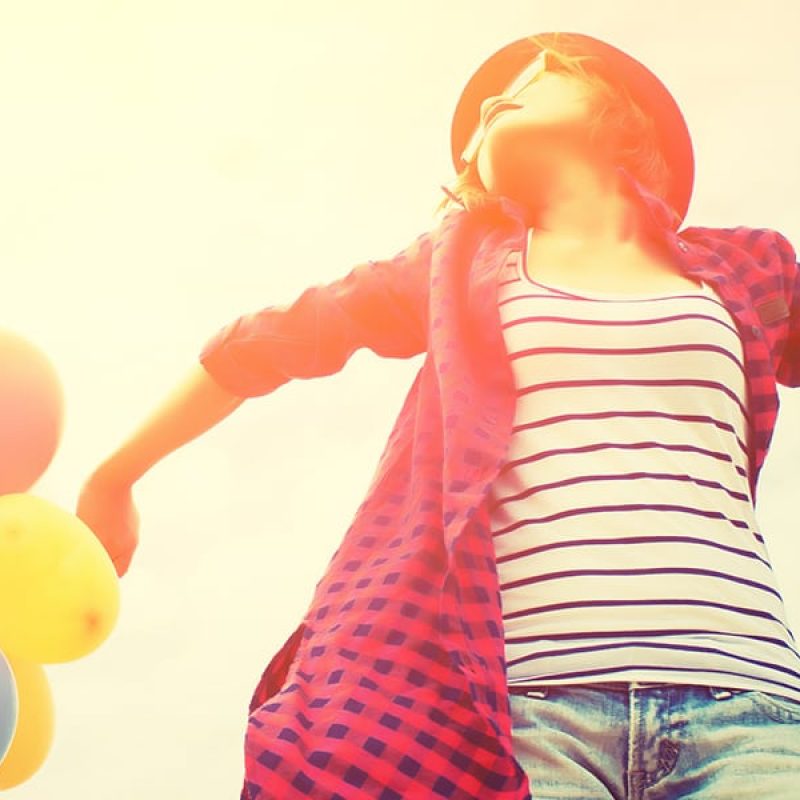 choose joy; joyful woman wearing pink and holding colorful balloons