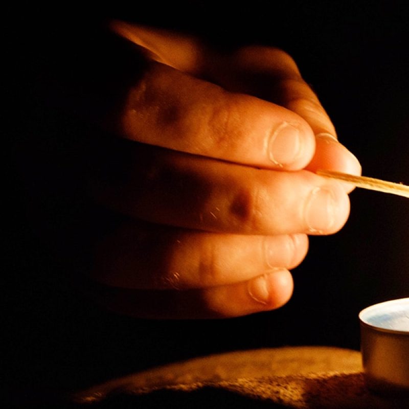 christmas eve: a holy pause; a hand lighting a candle with a match