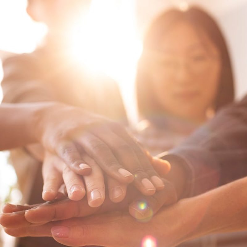 Group of diverse people unified stacking hands on top of each other as a symbol of teamwork