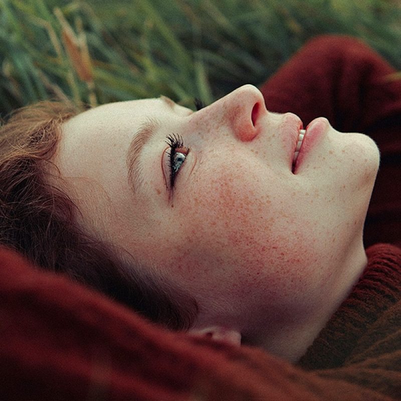 girl laying on her back in a field, looking upwards