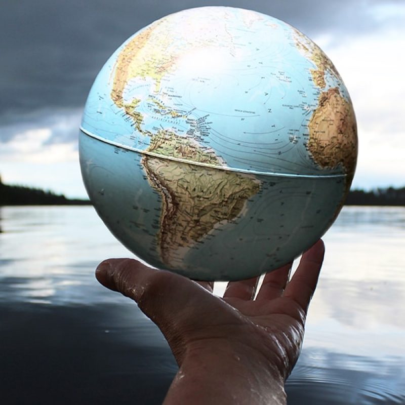 hand holding globe surrounded by nature