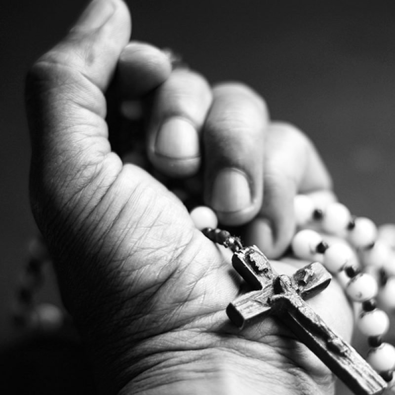 hand holding a rosary with a cross.