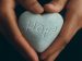 hands holding a stone heart with the word hope carved in it
