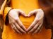 woman holding her hands forming a heart over her pregnant belly
