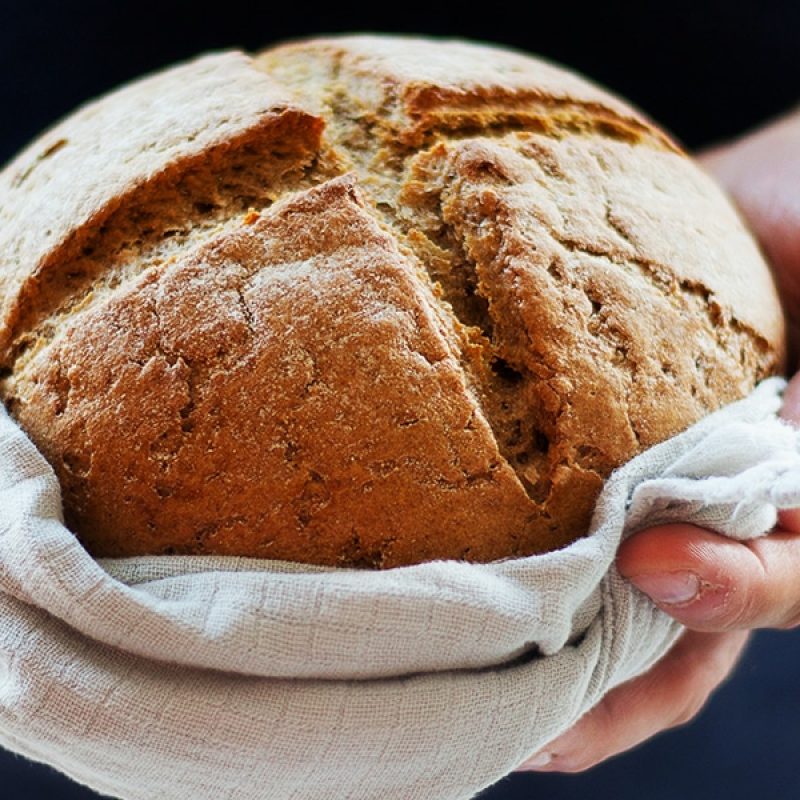 hands holding a fresh loaf of bread