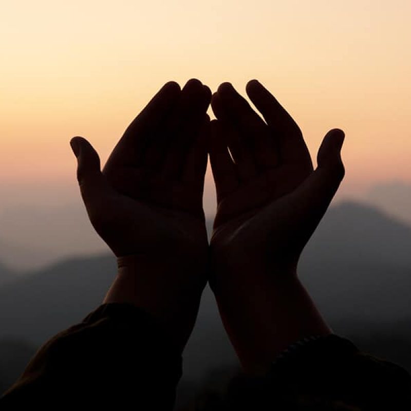 hands peaceful in worship with a sunrise in the background