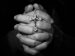hands folded in prayer while holding a rosary