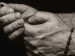 hands folded in prayer while holding a rosary