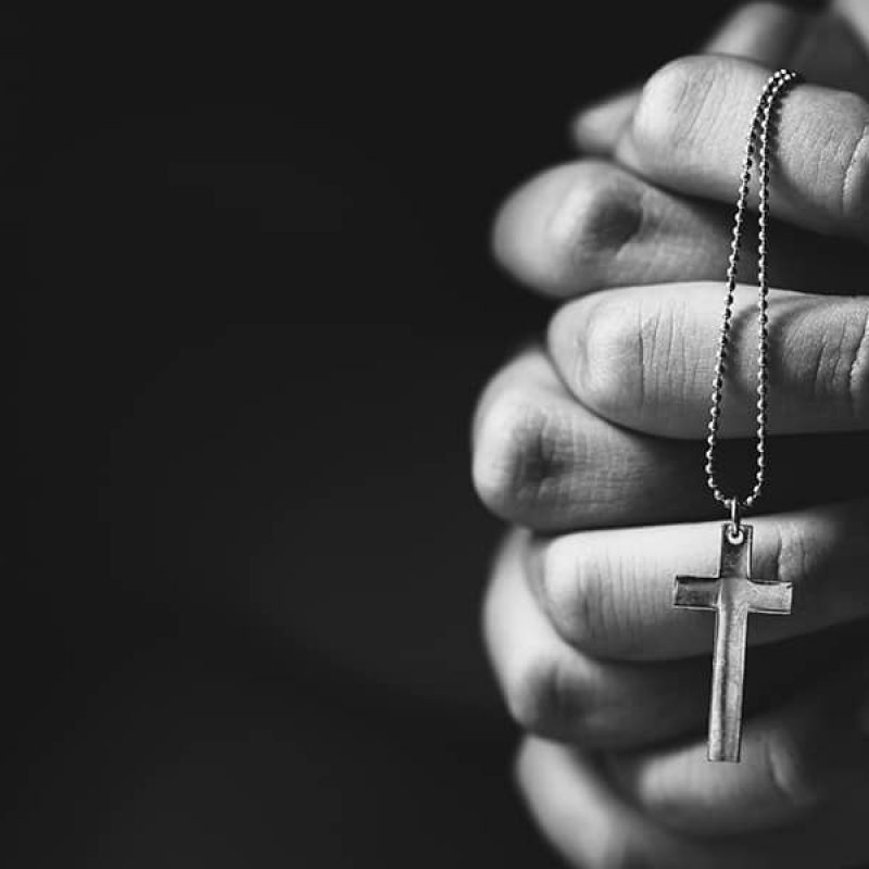 folded hands in prayer, holding a rosary