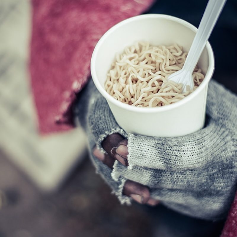 homeless person hold a cup filled with cuddles in his hands.