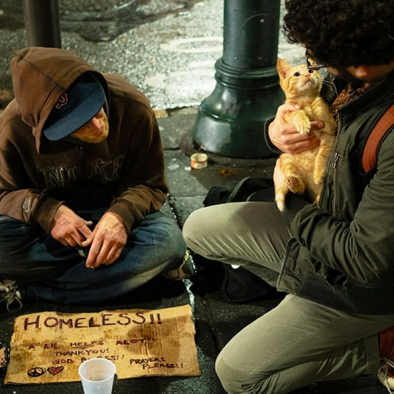 A man visiting a homeless person and having a conversation.