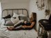 Person sitting with back against the wall on the bed holding coffee