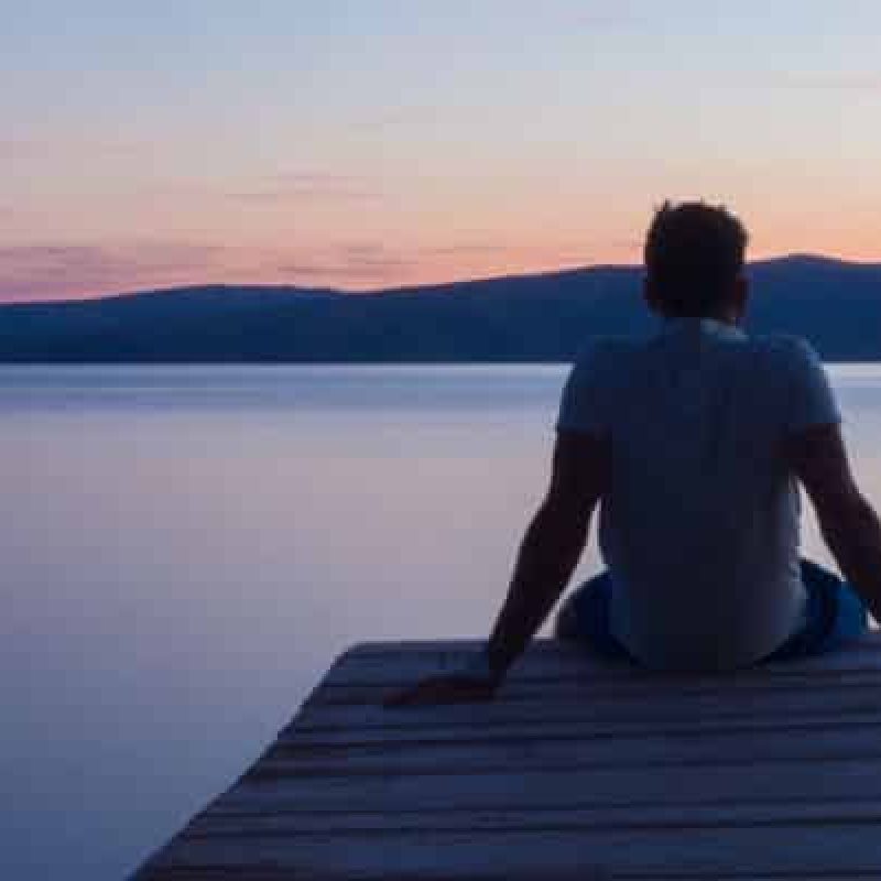 Man sitting at the endo of pier
