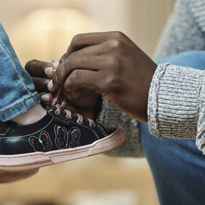 man tying a kid's shoe