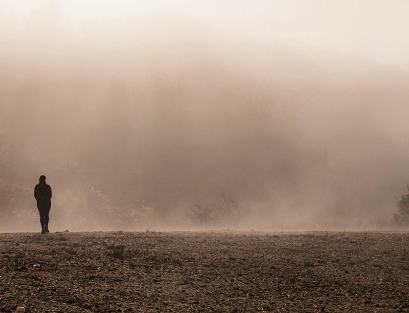 man walking in a field alone
