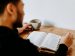 man sitting at a table reading his Bible