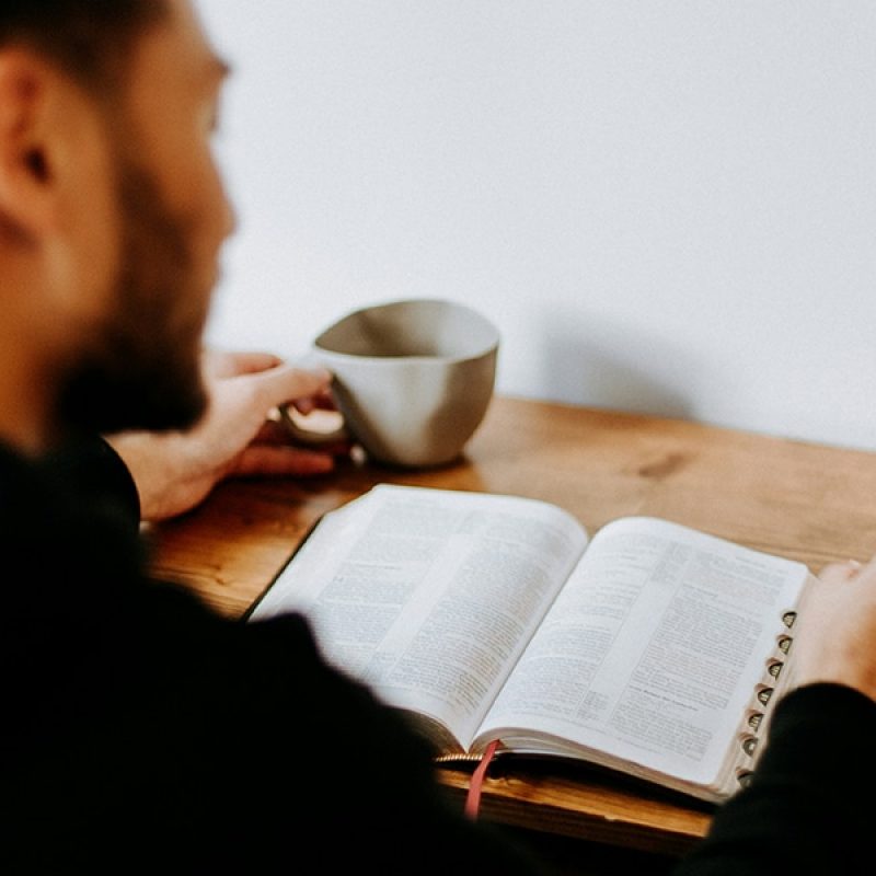man sitting at a table reading his Bible