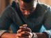 man with folded hands and bowed head praying