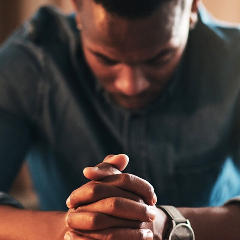 man with folded hands and bowed head praying