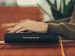 man resting hand on Bible while sitting in a chair