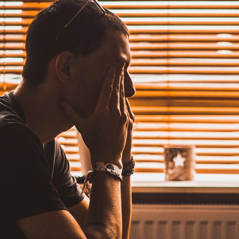 man holding his hands over his face.