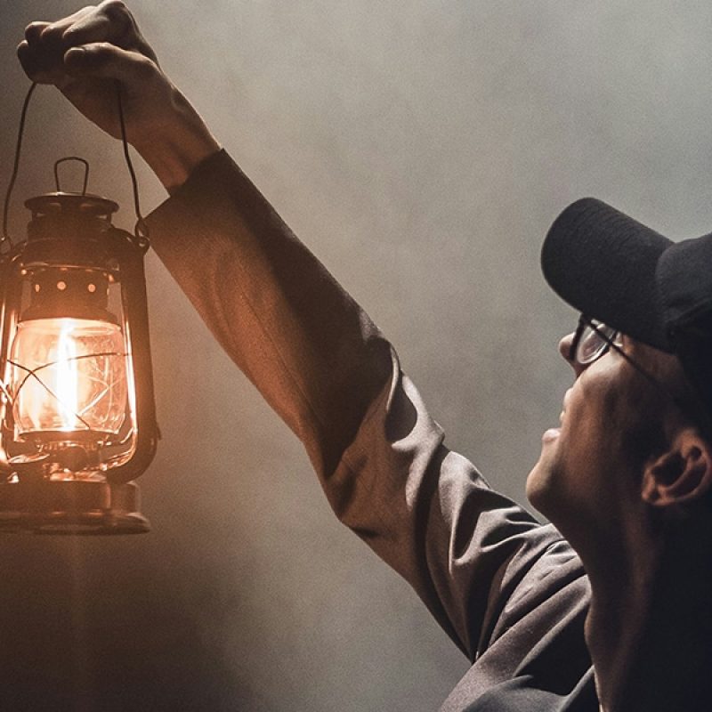 man holding a lantern, lighting up the room
