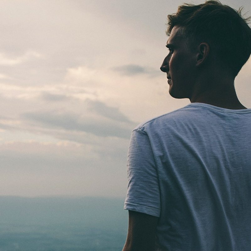 man standing on the mountain and looking into the distance