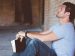 Man praying with his eyes closed while holding a Bible and leaning against a wall