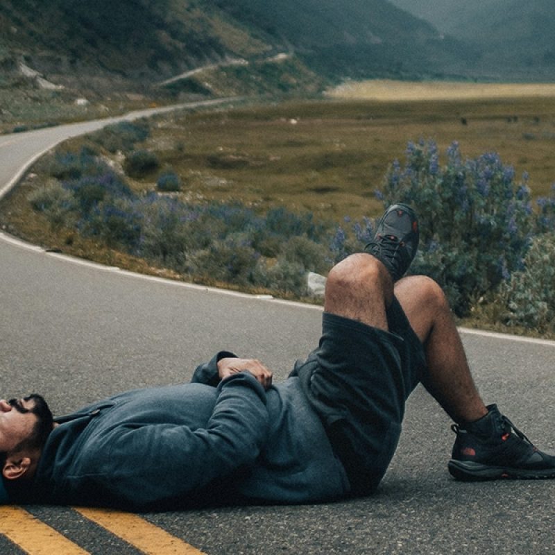 man laying down on road, looking up to the sky.