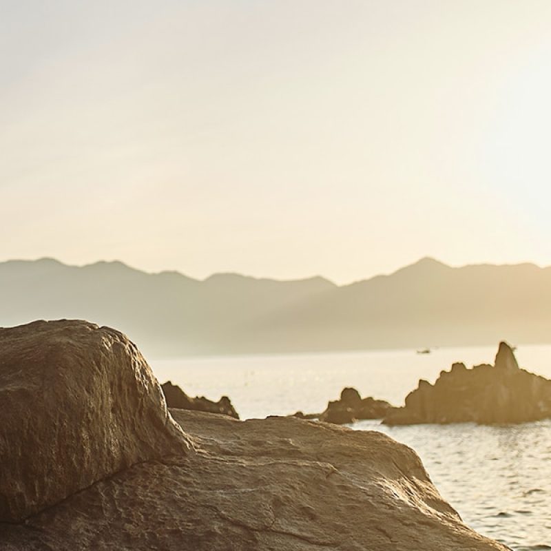 man standing on a rock in a bay.