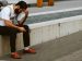 man being sad, resting his head in his hand, sitting outside