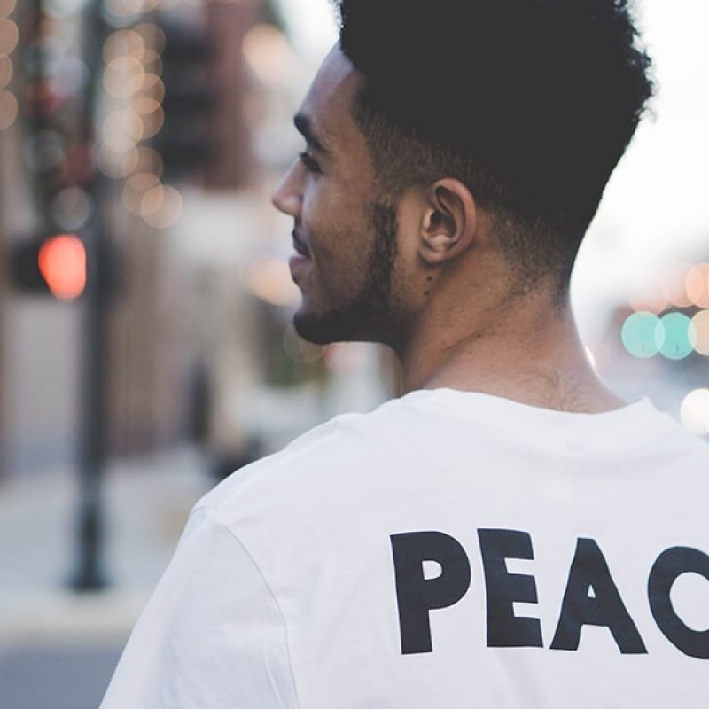 man wearing a t-shirt with the word Peace on the back.