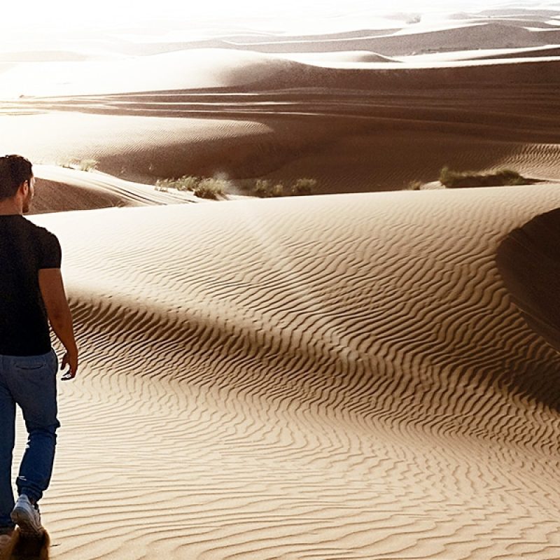 man walking in the desert, looking into the distance.
