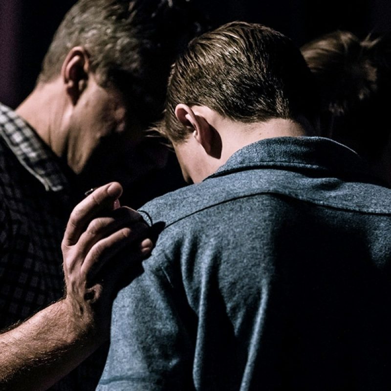 older man comforting younger man putting hand on his shoulder