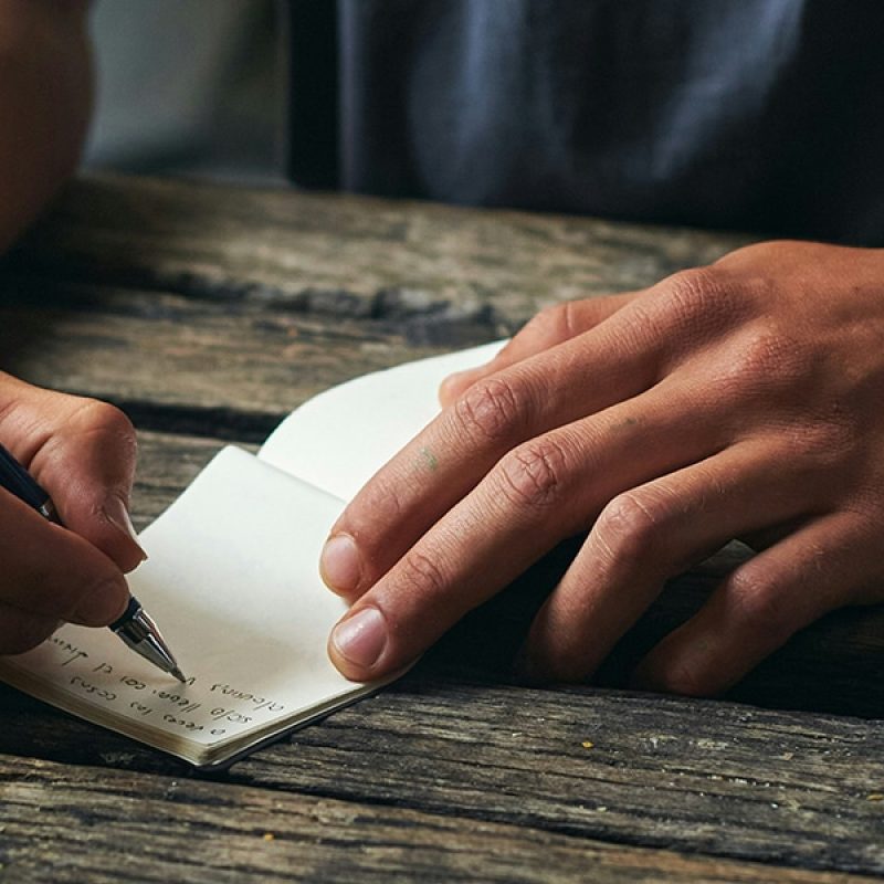 hand writing a note onto a piece of paper.