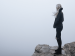 woman on a cliff surrounded by fog