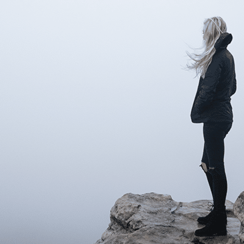woman on a cliff surrounded by fog