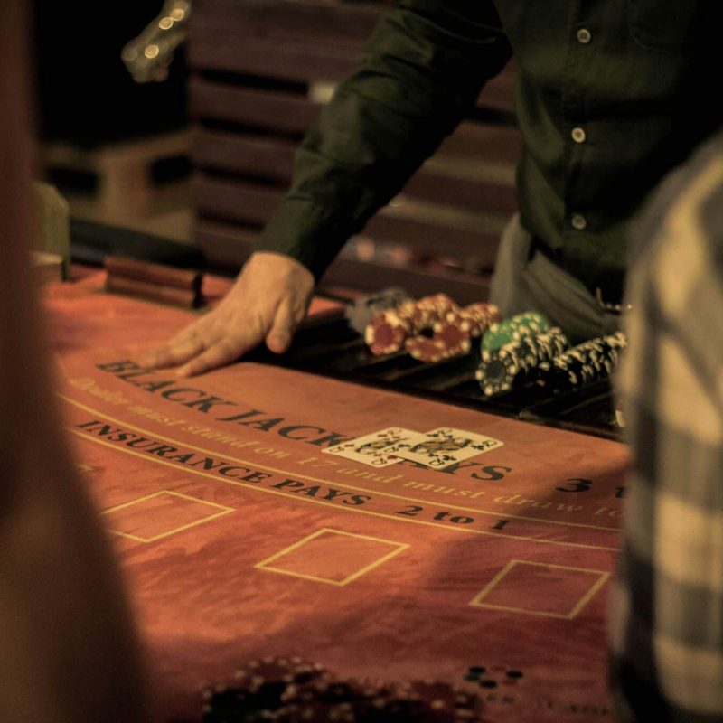 a person at a table with poker chips and cards | Photo by Dusan Kipic on Unsplash