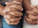 Two people praying together with folded hands.