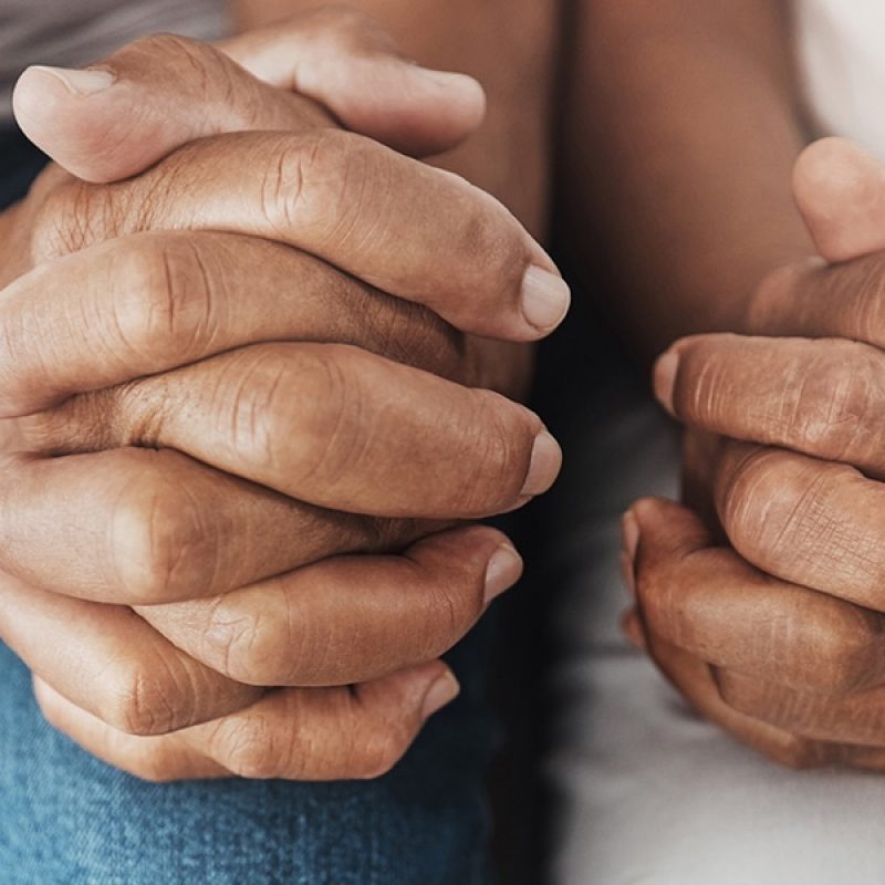 Two people praying together with folded hands.