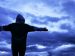person standing in front of a storm, surrounded by dark clouds.