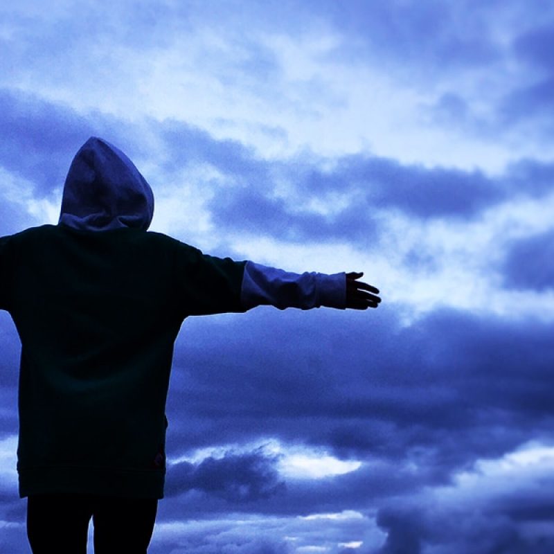 person standing in front of a storm, surrounded by dark clouds.