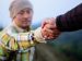 person reaching out a hand to help pull a man up.