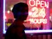 person in front of a open twenty four hours neon sign.